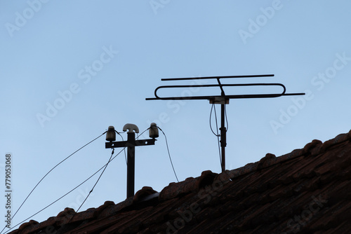 an old antenna for receiving television and radio broadcasts on the roof of an old house and an old connection to a wired radio