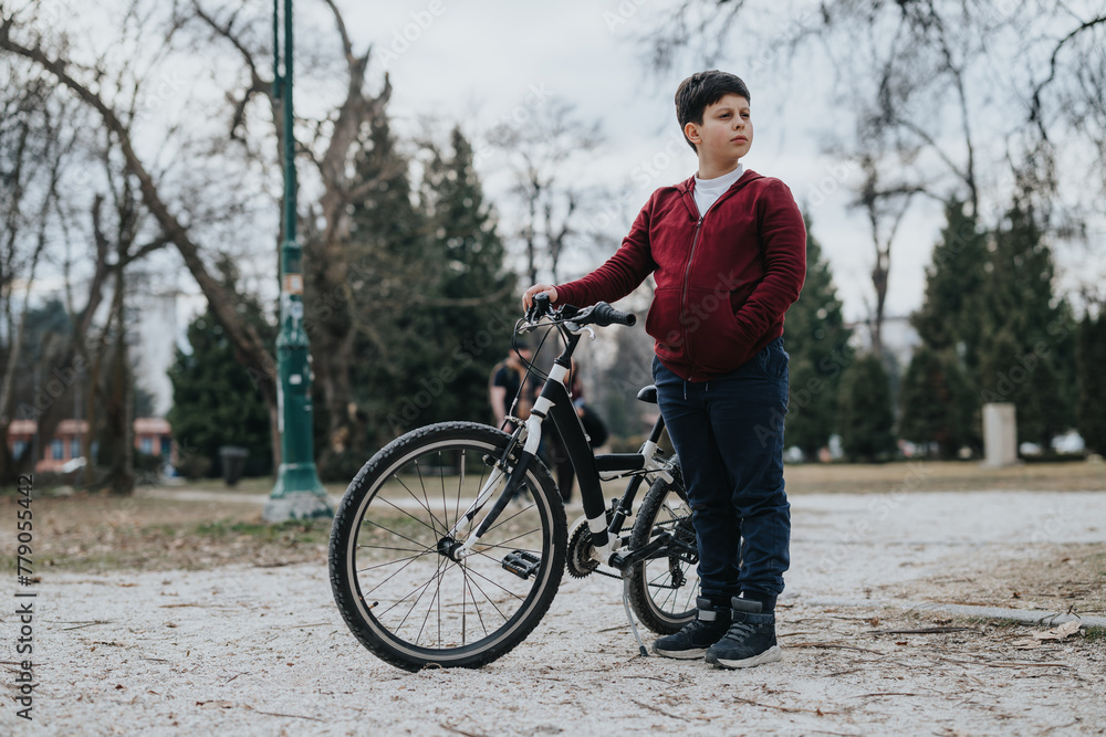 A joyful young kid standing with his bike outdoors in a park, showcasing an active and carefree childhood moment.