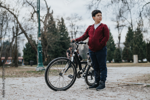 A joyful young kid standing with his bike outdoors in a park, showcasing an active and carefree childhood moment.