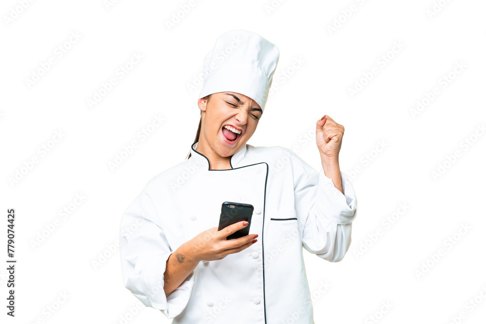 Young woman Chef over isolated chroma key background with phone in victory position Young woman Chef over isolated chroma key background with phone in victory position