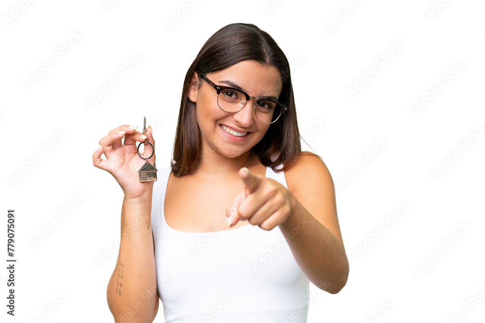 Young caucasian woman holding home keys isolated on green chroma background points finger at you with a confident expression Young caucasian woman holding home keys isolated on green chroma background points finger at you with a confident expression