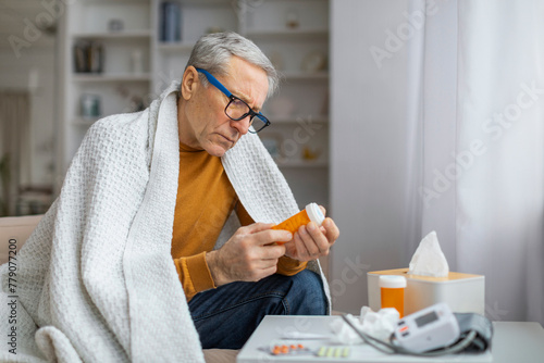 Senior man with medications examining pill bottle photo