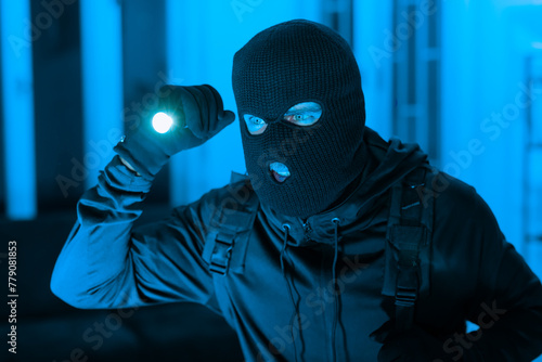 Fotografie Masked figure with flashlight in blue tone