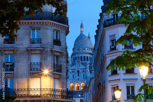 The famous Sacre-coeur basilica between haussmann buildings in Paris in the evening . France.
