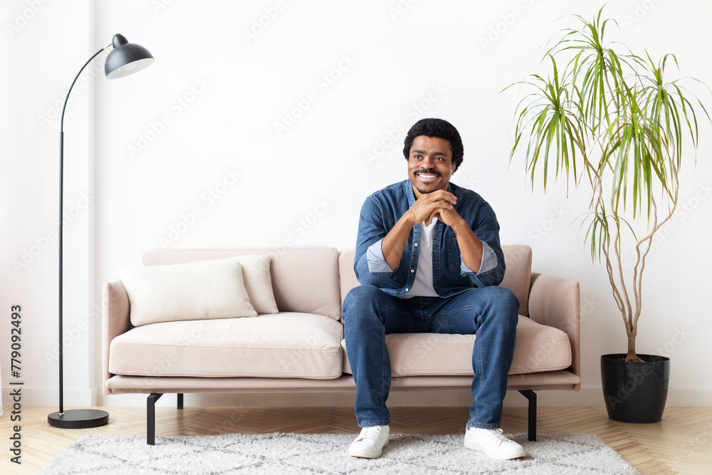 Fototapeta premium Black Man Sitting On Couch in Living Room And Smiling