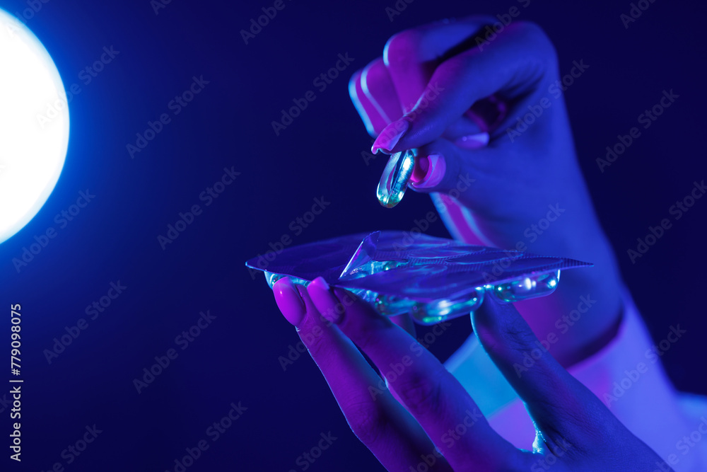 hand takes a pill out of the package close-up in ultraviolet color hand takes a pill out of the package close-up in ultraviolet color