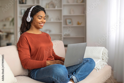 Black Woman In Headphones Sitting on Couch Using Laptop