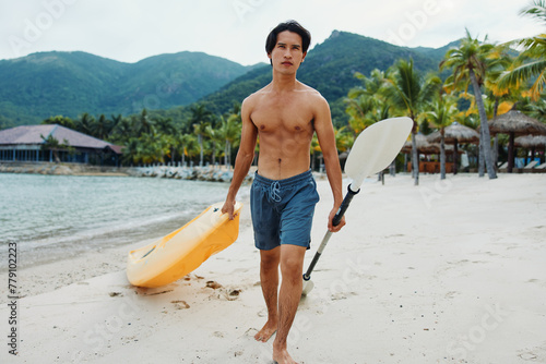 Happy Asian Man Kayaking in Tropical Beach Paradise photo