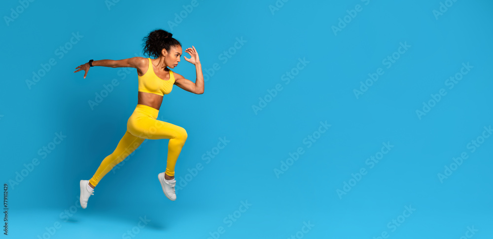 Dynamic athlete black woman in mid-jump on blue background Dynamic athlete black woman in mid-jump on blue background