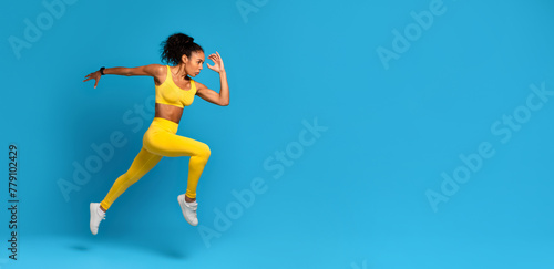 Dynamic athlete black woman in mid-jump on blue background