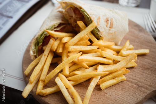 Stuffed tortilla chicken wrap with vegetables and french fries