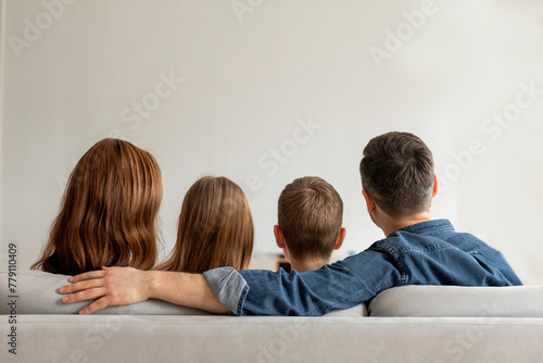 Family sitting together on a couch, rear view