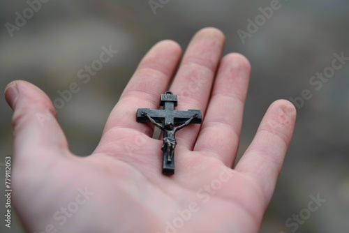 Left palm of one hand holding a small crucifix