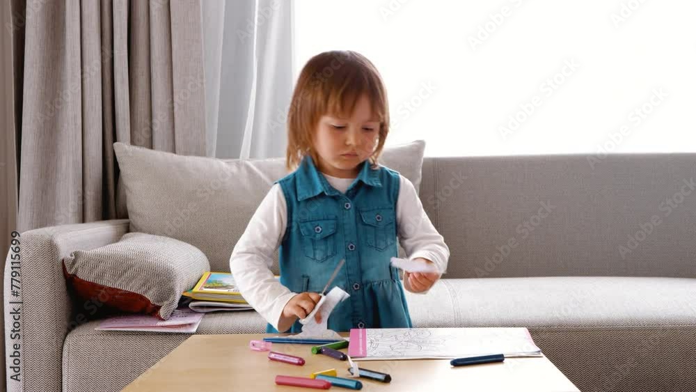A girl cuts out a paper figure with scissors. Children's development A girl cuts out a paper figure with scissors. Children's development