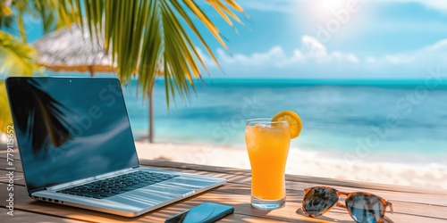 A workcation setup with a laptop and orange juice on a beach bar capturing the essence of a relaxed work environment.