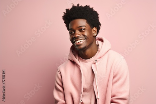 A young man with a big smile is wearing a pink hoodie
