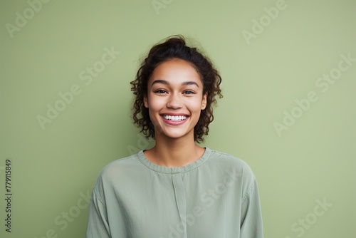 A woman with curly hair is smiling and wearing a green shirt