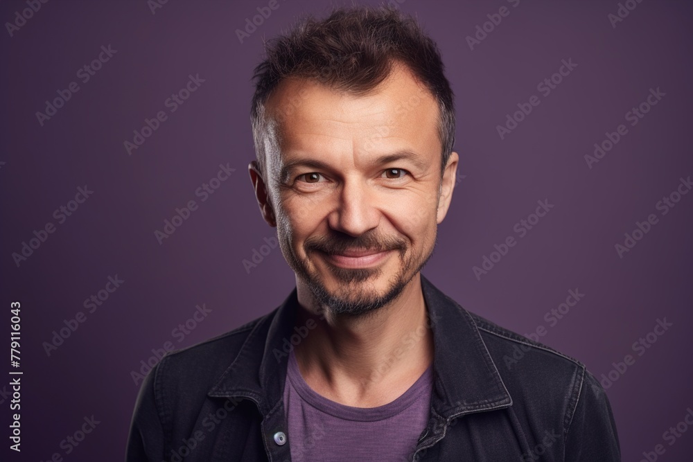 A man with a beard and a smile is standing in front of a purple background A man with a beard and a smile is standing in front of a purple background