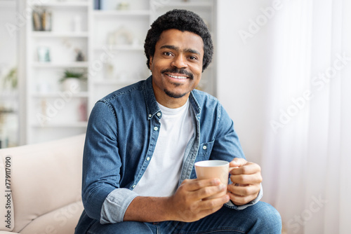 Man Sitting on a Couch Holding a Cup of Coffee