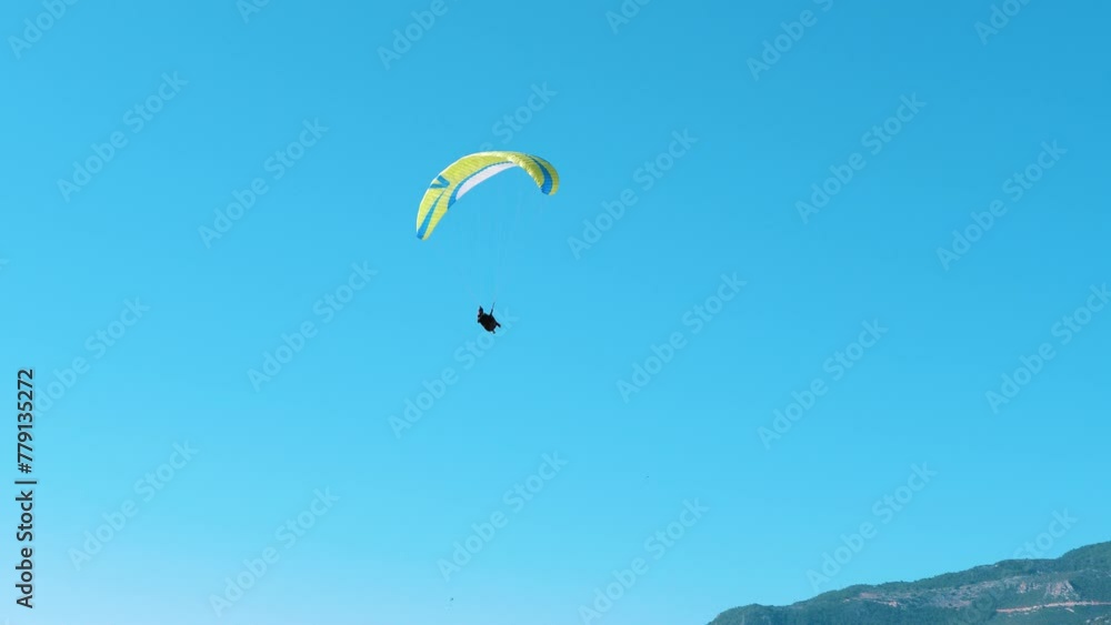 The paraglider flies against the blue sky. The paraglider flies against the blue sky.