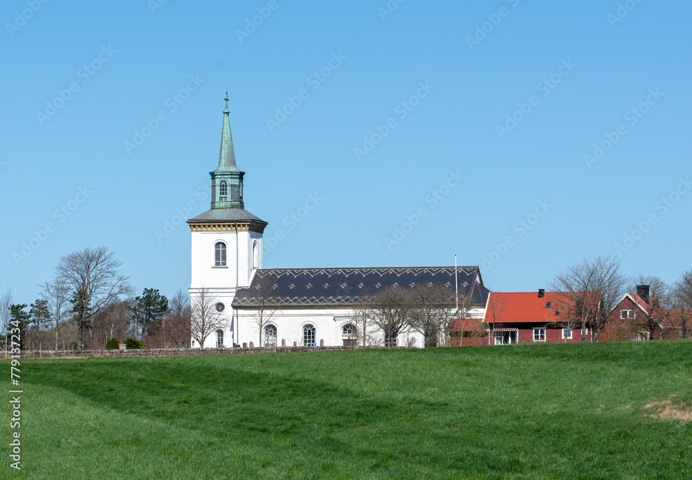 White church with red buildings and stone wall
