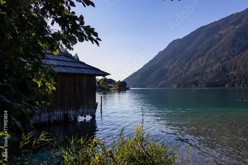 Wooden bathing house at east bank of alpine lake Weissensee in Gailtal Alps, Carinthia, Austria. Scenic Lakeside Retreat in serene landscape amidst untouched nature in summer. Remote boat house photo