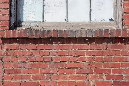 Dirty and crumbling brick work around a window ledge