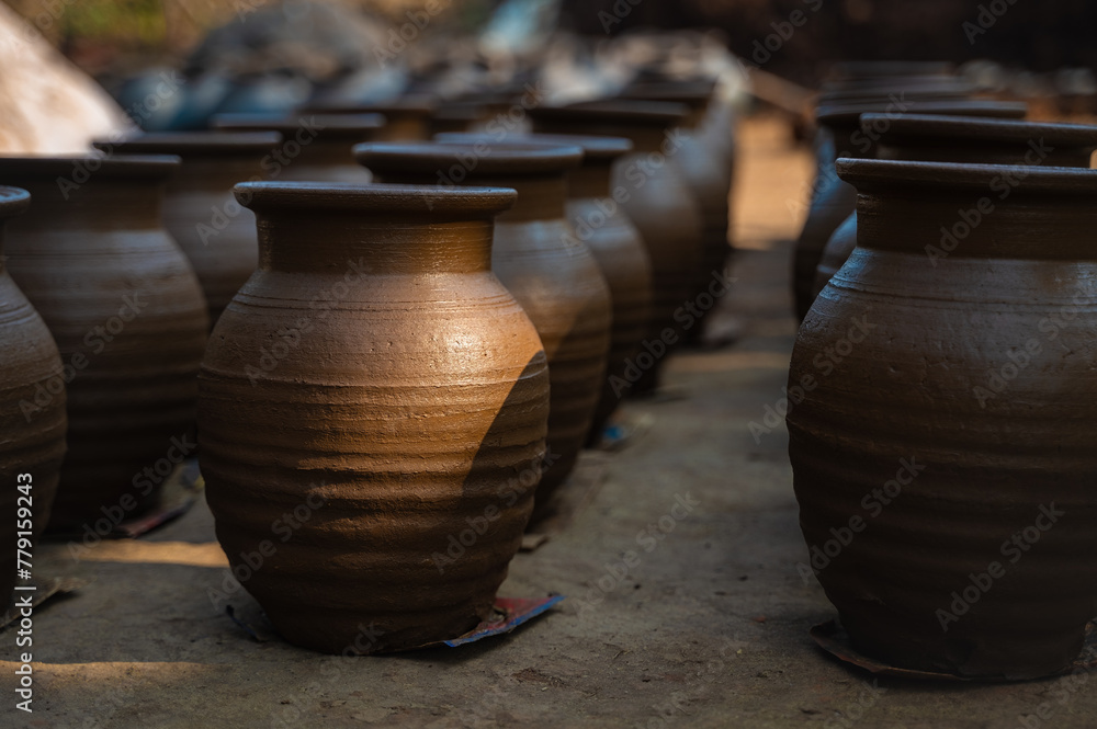 Earthen mud pots placed in rows for drying during morning. Sunlight on the mud pot. Selective focus. Earthen mud pots placed in rows for drying during morning. Sunlight on the mud pot. Selective focus.