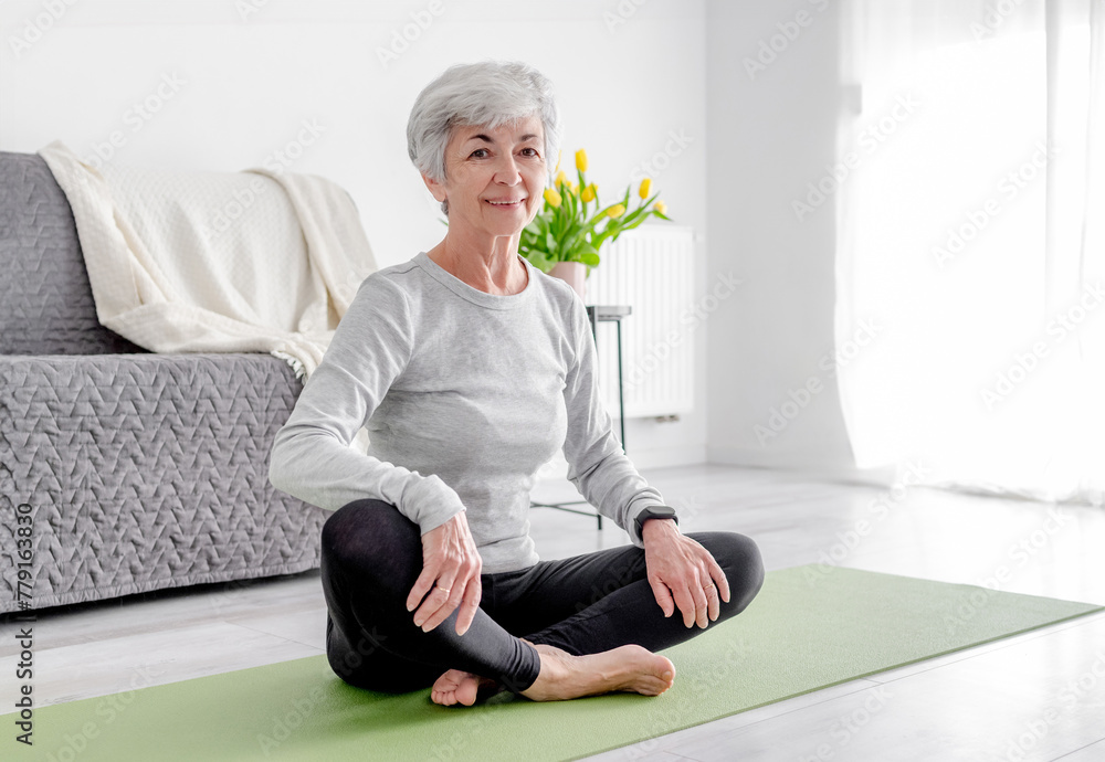 Obraz premium Sweet Woman Looks Into Camera While Sitting On Yoga Mat, Embodying Active Lifestyle, Practicing At Home