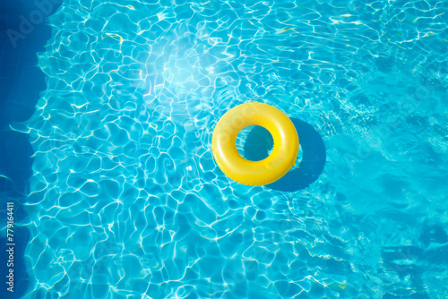Yellow pool float, ring floating in a refreshing blue swimming pool.