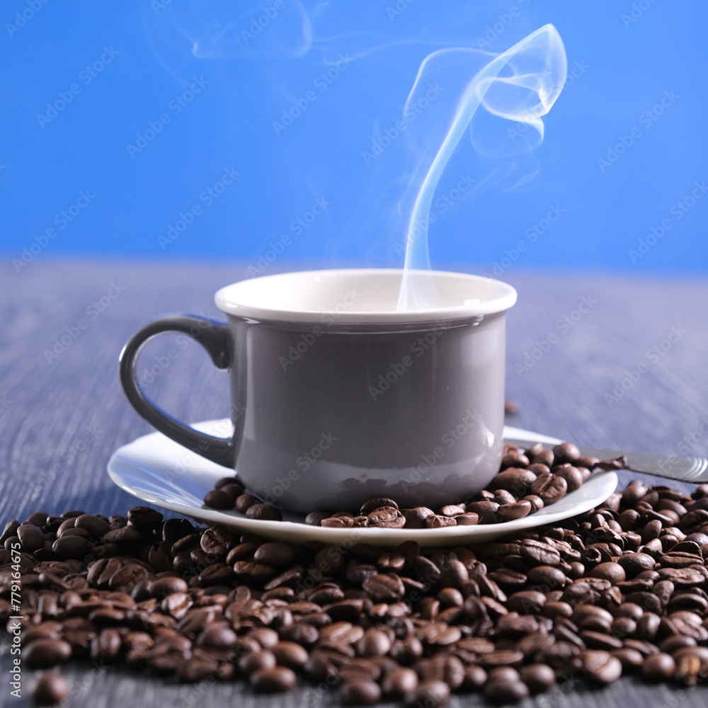 Fototapeta premium Tazza di caffè fumante sul piattino con chicchi di caffè