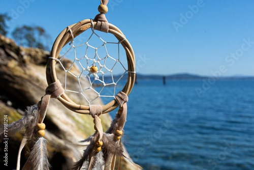 An image of a handmade dreamcatcher with the blue Pacific Ocean in the background.