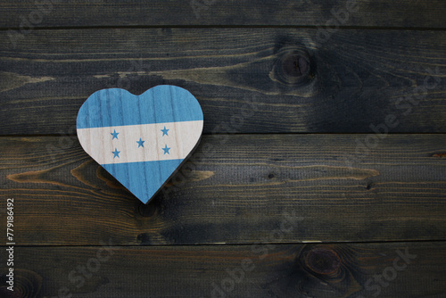 wooden heart with national flag of honduras on the wooden background.