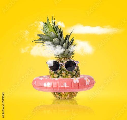 Pineapple with ring float and sunglasses on a yellow background. Creative concept summer beach holiday
