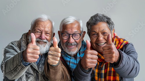 Groupe de trois amis âgés, 60 à 70 ans, levant le pouce vers le ciel, fond blanc, sortie entre seniors photo