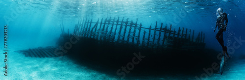 Silhouette of free diver exploring ship wrack.