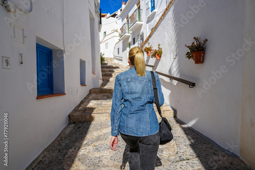 Blond woman walking stairway in white village of Frigiliana Spain