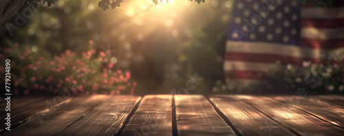 An idyllic American patriotic scene with a wooden surface in the foreground, soft focus flowers, and a blurred USA flag in the warm, glowing sunlight photo