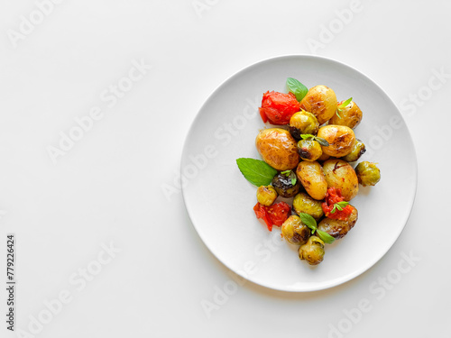 Overhead view of plate with roasted baby potatoes, Brussels sprouts, and cherry tomatoes garnished with fresh basil, clean eating concept with copy space.