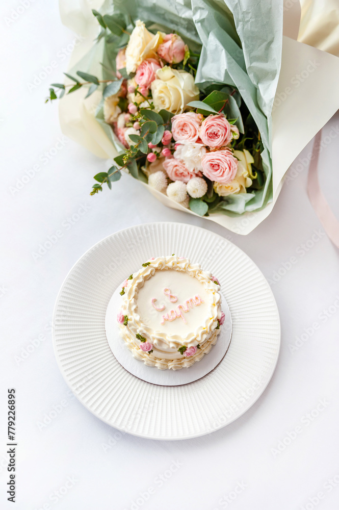 Festive bento cake and bouquet on a light background