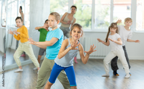 Group of children training movements of twist in dance studio with female tutor
