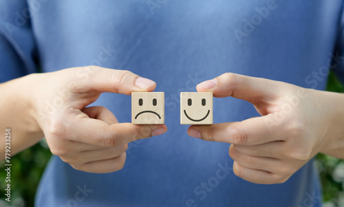 Choosing emotions with wooden block. Holding wooden cubes with happy and sad faces, concept of choosing your attitude or emotion. Customer review satisfaction feedback survey, Mental health assessment