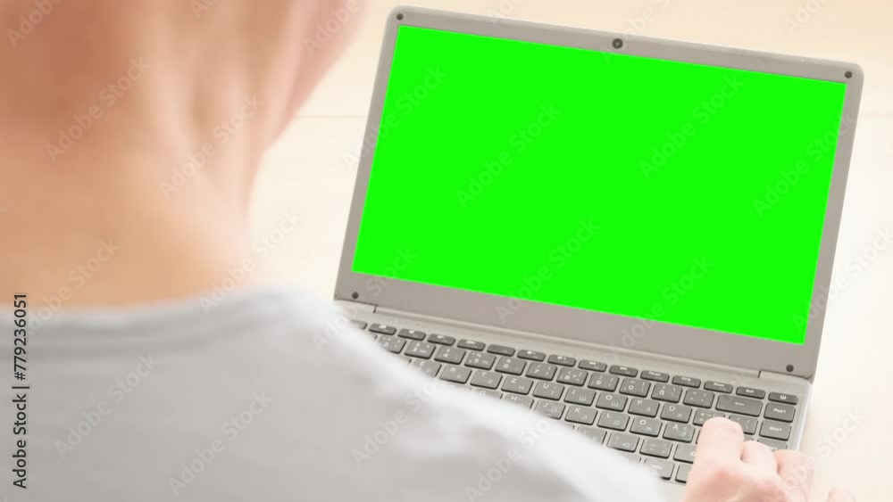 Over shoulder view elderly man hesitantly uses laptop, green screen ...