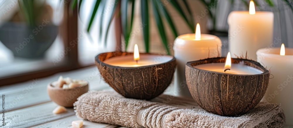 Several candles are softly glowing inside coconut bowls placed on a cloth on a tabletop - obrazy, fototapety, plakaty 