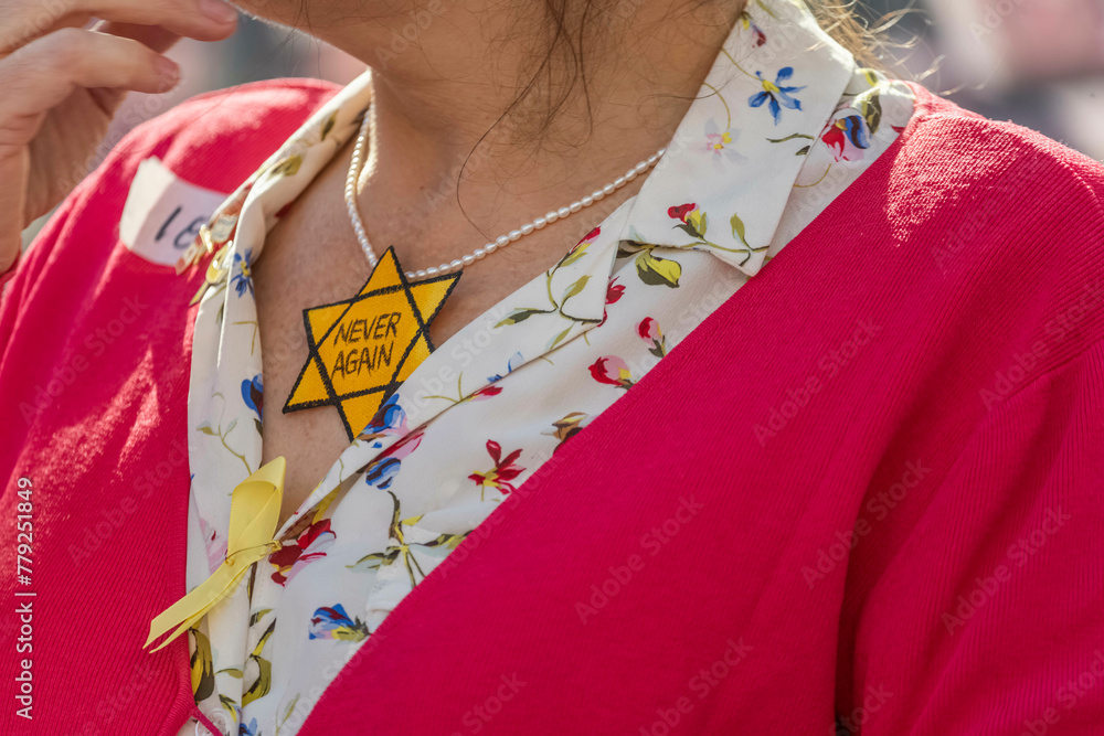 A lady wearing a yellow star with the words never again.