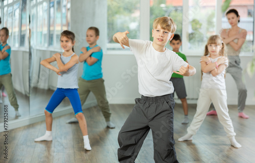 Children studying modern style dances with female teacher in dance class indoors