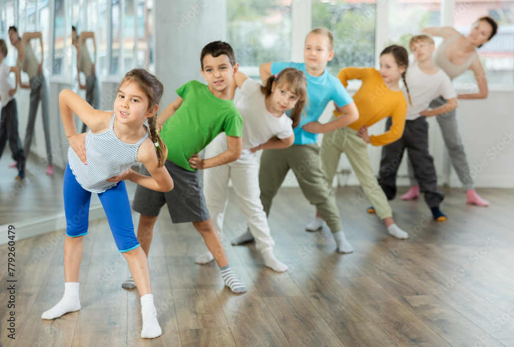 Children do warm-up exercises in studio, prepare for pair dance class with teacher. Active lifestyle, extracurricular activities.