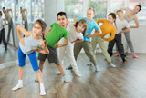 Children do warm-up exercises in studio, prepare for pair dance class with teacher. Active lifestyle, extracurricular activities.
