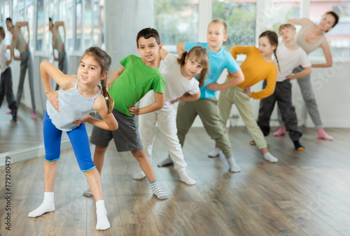 Children do warm-up exercises in studio, prepare for pair dance class with teacher. Active lifestyle, extracurricular activities. © JackF