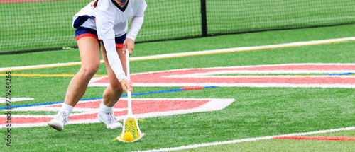 Girls lacrosse player scooping up the ball during a game
